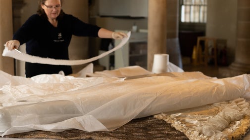 A textile conservation worker lays down the peacock dress at Kedleston Hall.